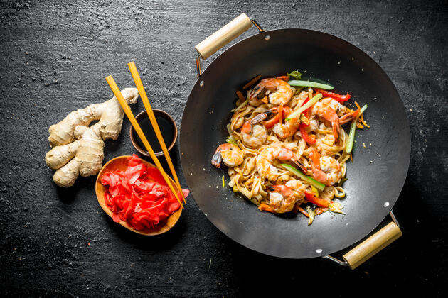 美味美味的乌冬炒面配上新鲜蔬菜 酱汁和虾放在黑色的木桌上顶视图亚洲准备