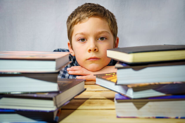 阅读一个悲伤的男孩躺在孩子们的书中 站在木桌上的画像男孩孩子学生