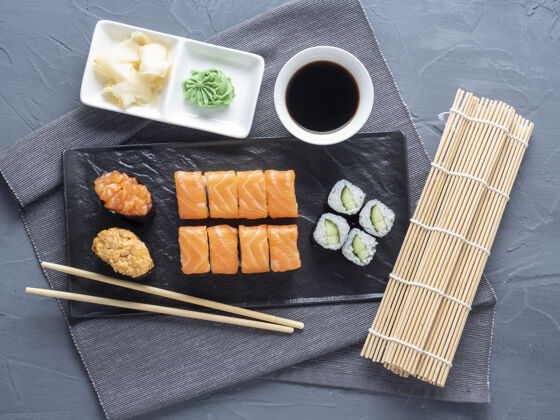 新鲜各种各样的面包卷和寿司堆在黑色的桌子上板下一个它是竹芥末棒和酱汁.上衣视图 平面传统的日本料理日本传统Maki