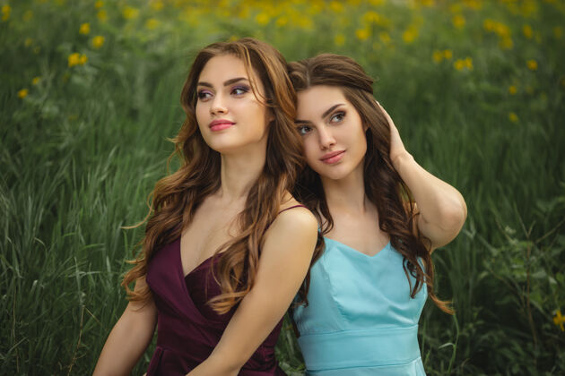 两个坐在绿草如茵 妆容和发型完美的时尚双胞胎模特写真女人美丽白种人