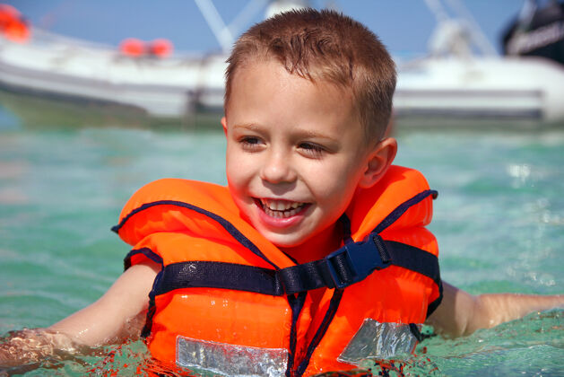 度假一个在海上穿着救生衣的快乐男孩水手救生男孩
