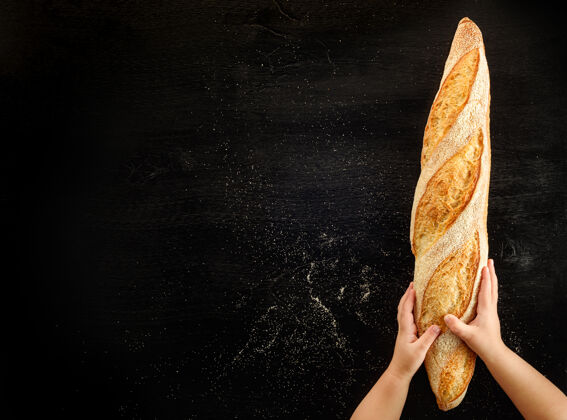 观点孩子们的手拿着黑色背景上的法式面包杂货店面包面包