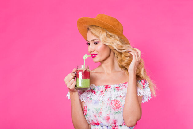 新鲜年轻漂亮的女人 在粉红色的墙上贴着绿色的冰沙 还有文字空间冰沙蔬菜饮料