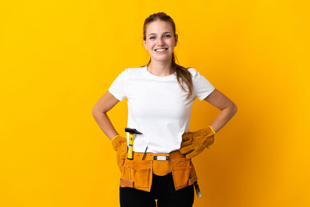 自信被隔离在黄色背景上的年轻电工妇女 双臂抱在臀部 面带微笑女孩年轻成人