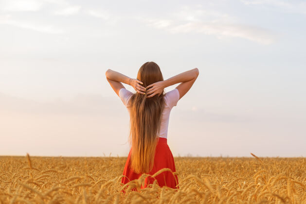 假期年轻女子站在小麦中间fields.后部风景很美长头发自然的美女乐趣黄金自由