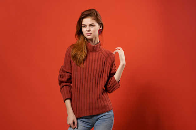 年轻穿着红色毛衣和牛仔裤的时髦女人休闲装摆出孤立的背景头发看起来清洁
