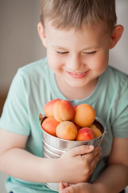 冰沙一个4岁的可爱小男孩正在吃桶里的多汁杏子果汁菜肴夏天