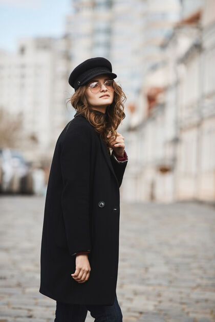 牛仔裤户外春季写真 年轻优雅时尚的女人戴着时髦的太阳镜 红色外套和帽子走在欧洲城市的街道上太阳镜模特配饰