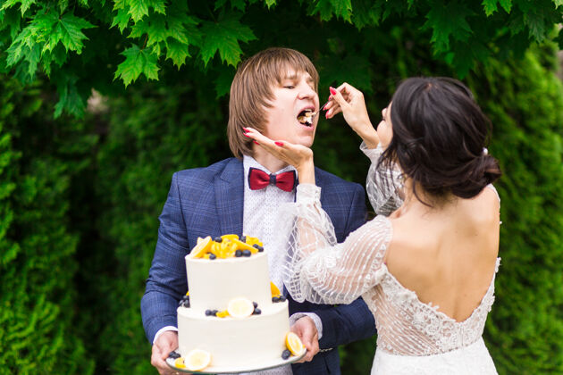 聚会新婚夫妇和伴娘们在婚宴上尽情享受 在新鲜空气中一起吃结婚蛋糕食物朋友蛋糕