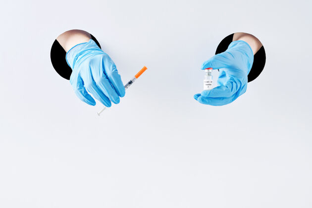 疫苗预防冠状病毒疫苗在防护医用蓝手套中手穿白纸洞.疫苗接种预防传染病的疫苗疾病医院医疗保健