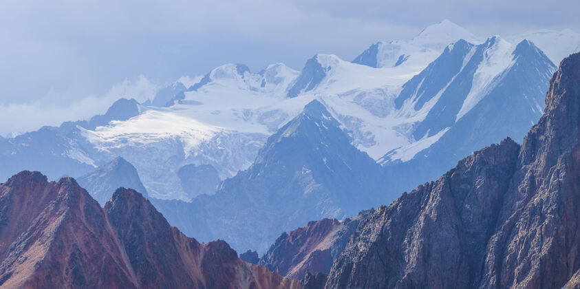 岩石蓝色雾霭中白雪皑皑的山峰山脉山高山