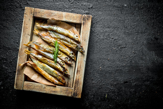 美味木头上的熏鱼托盘.on黑色乡村背景菜肴波罗的海新鲜