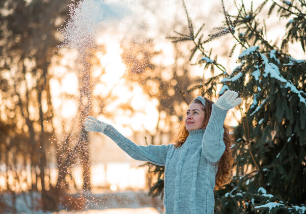 毛衣快乐美丽的年轻女子穿着灰色温暖的毛衣吹雪花从她的手在冬天的一天姿势模型雪