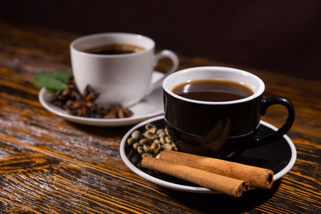 棒一对肉桂棒和咖啡豆放在咖啡杯碟里 放在深色的木桌上木材意式浓缩咖啡杯子