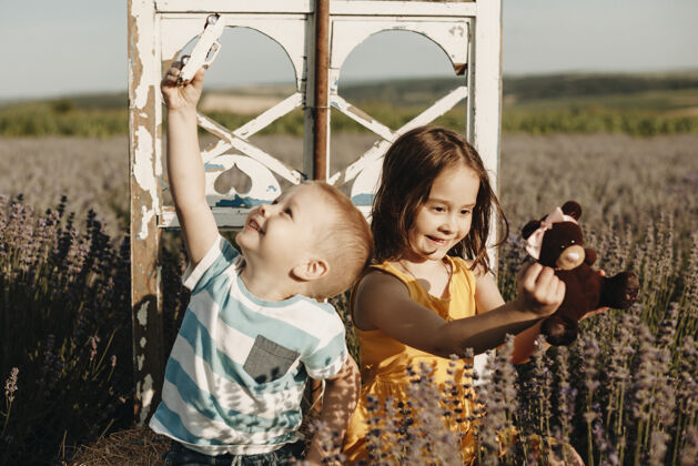 自由可爱的小男孩和她的小妹妹在户外的花丛里玩耍活跃友谊汽车