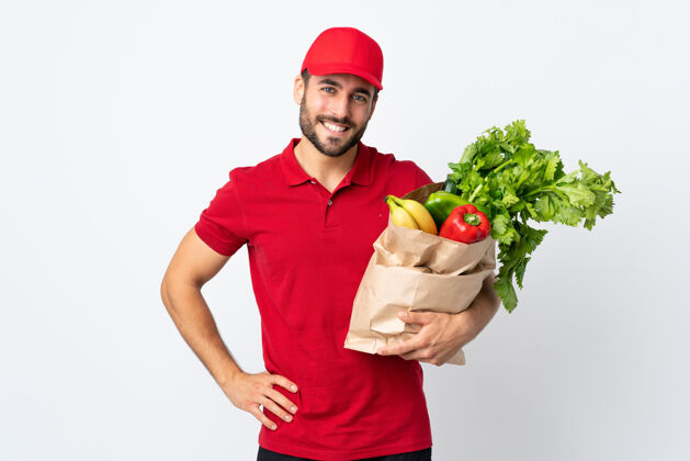 有机一个留着胡子的年轻人拿着装满蔬菜的袋子 在白色的背景上笑着新鲜送货健康