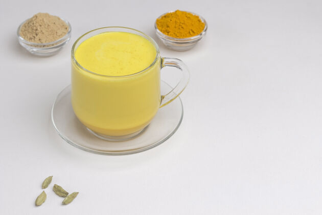 香料印度姜黄黄金牛奶在玻璃与烹饪原料草药健康健康食品