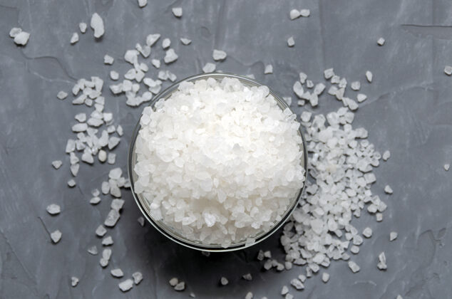 抽象粗糙的白色海盐在一个玻璃碗里撒在桌子上谷物木材调味品
