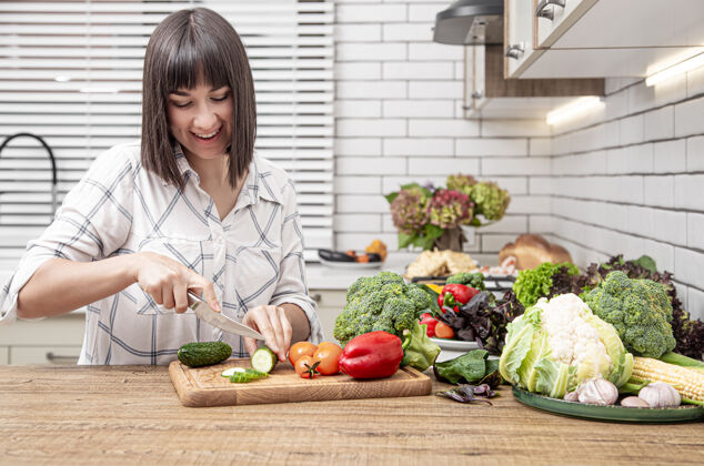 素食主义者年轻的黑发女人在现代厨房内部空间的沙拉上切蔬菜室内维生素黑发的