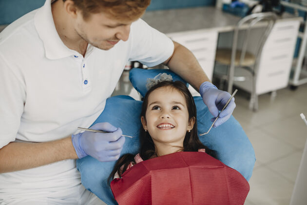 卫生可爱的小女孩微笑着看着她年轻的儿科口腔医生在做牙齿检查口腔办公室美丽