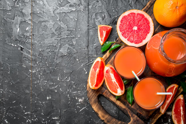 玻璃把成熟的葡萄柚汁放在砧板上的罐子里葡萄柚素食水果