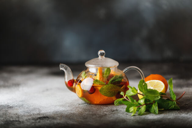 提神水果茶配薄荷 橙子和红莓 背景为深色石头一杯热茶饮料健康的新鲜