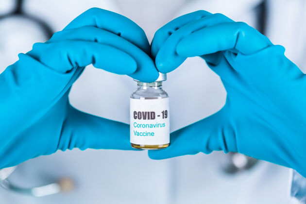 实验室女医生或护士穿着制服 戴着手套 戴着口罩 在实验室里拿着一种形式的心脏药瓶 疫苗瓶上贴着冠状病毒-19疫苗标签护理病毒流行病