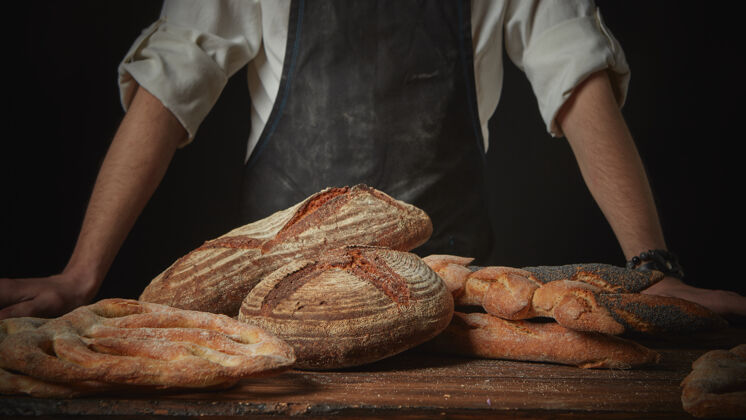 乡村面包师傅用新鲜的面包放在木制的棕色桌子上面包师温暖无麸质