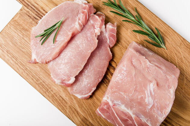 牛腰肉生肉片木面迷迭香平板躺在木头上板关闭-向上看烹饪蛋白质牛排