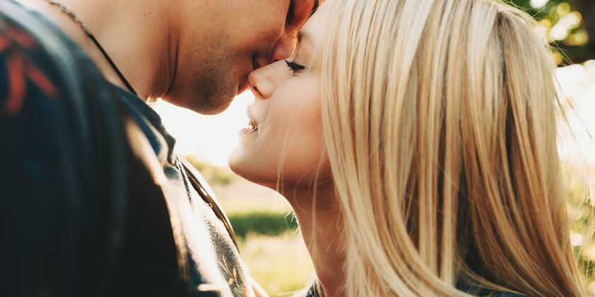 在一起一对在阳光下亲吻的情侣的特写镜头浪漫男性女孩
