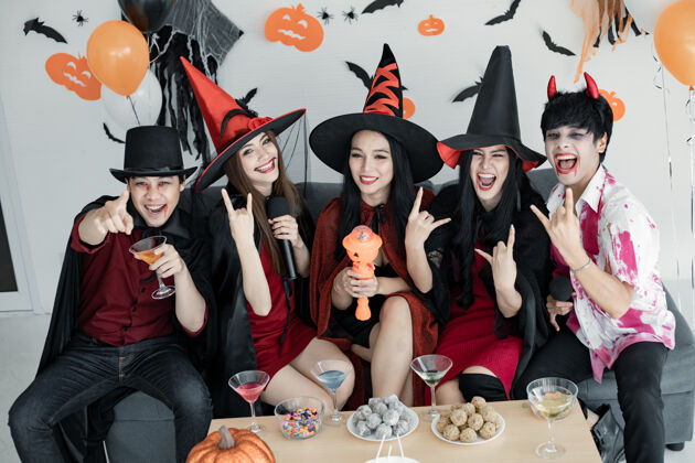 十月一群年轻的亚洲人穿着女巫的服装 和巫师一起欢庆万圣节派对 为他们唱歌喝酒 吃甜点房间.组泰语青少年万圣节概念在家里过万圣节万圣节微笑眼镜