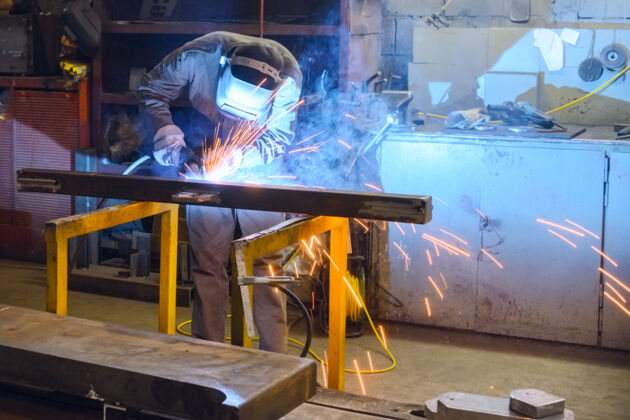 危险工作焊工在工厂焊接零件采用半自动焊接的过程工人制造研磨