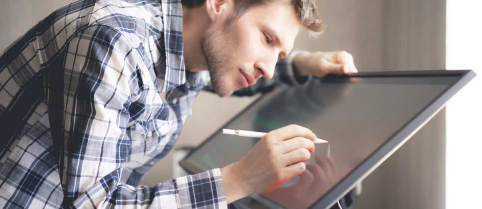 商务人员一位年轻的男性数码艺术家在工作室的电脑屏幕上画画教育平板电脑技术