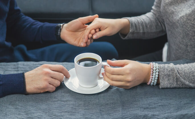 杯子一男一女端着一杯咖啡坐在桌边男性情侣日期