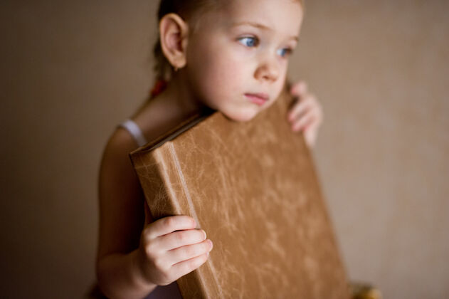 材料一个小女孩拿着一本棕色天然皮革的相册记忆配件摄影师