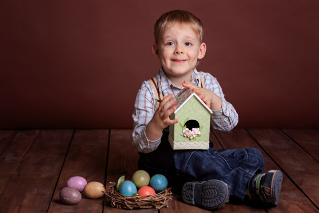 复活节复活节小男孩玩具五颜六色柳条窝里的复活节彩蛋 鸟的鸟舍肖像五颜六色绿色