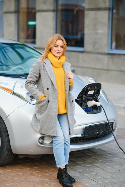 生态在加油站给电动车充电的女人交通移动停车