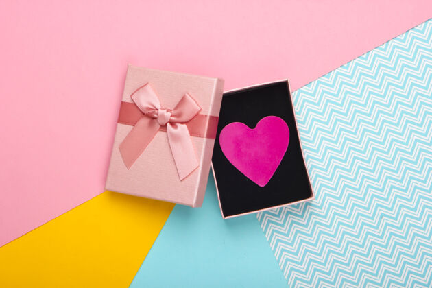 精致彩盒上有蝴蝶结和装饰心形的礼品盒背景：圣瓦伦丁的粉彩颜色趋势.top查看问候平铺对象
