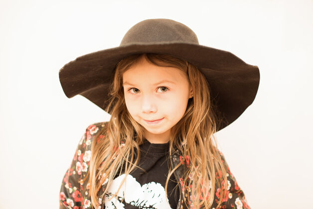 孩子白墙上戴着黑色大帽子的时髦小女孩乐趣女性时尚