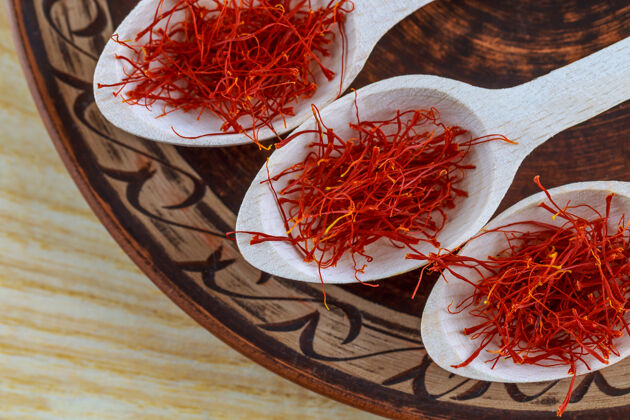 自然木藏红花勺子干的放在陶瓷盘子上的木勺里的藏红花香料盘子季节干燥