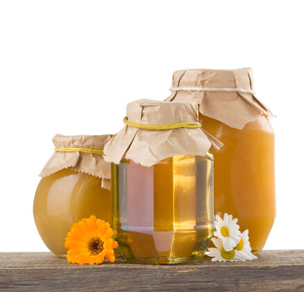 健康蜂蜜和花隔离在白色玻璃配料罐