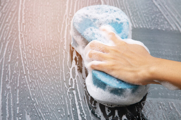 车辆人民工人男子手拿蓝色海绵和泡沫洗面奶泡沫窗口洗车城市泡沫海绵