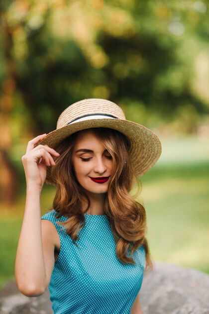 优雅公园里一个穿着蓝色裙子戴着优雅帽子的时髦女孩的画像发型女士花园