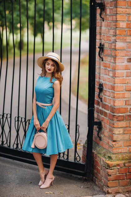 化妆街上穿着蓝色连衣裙戴着优雅帽子的时髦女孩优雅青年女士