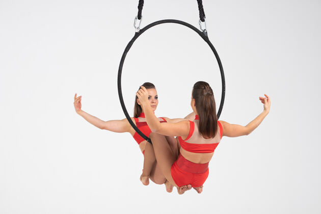 马戏团双胞胎女马戏团艺术家在空中环上孤立的白色情侣艺术家运动员