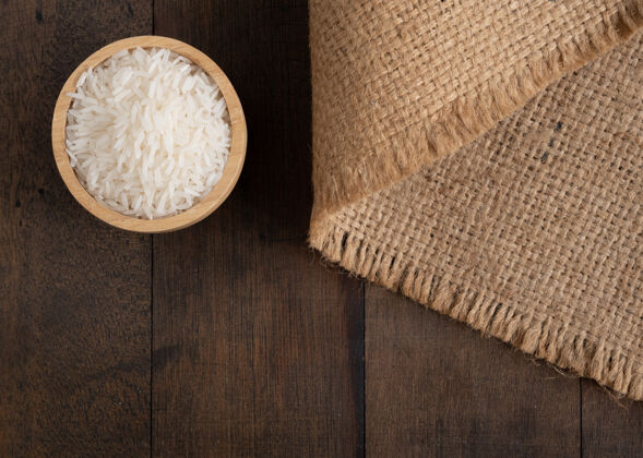 谷物茉莉花米饭放在麻布木碗里 麻布麻布桌子的背景与复印空间 顶视图自然新鲜茉莉