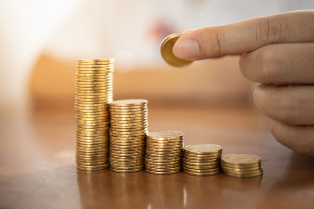未来商业 金钱 金融 安全和储蓄概念关闭站起来的人手里拿着硬币 把一堆金币放在木桌上成本增长商人
