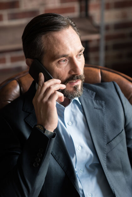 沟通业务问题很好长着大胡子的帅哥商人 耳边拿着手机 边工作边讨论房间手机连接