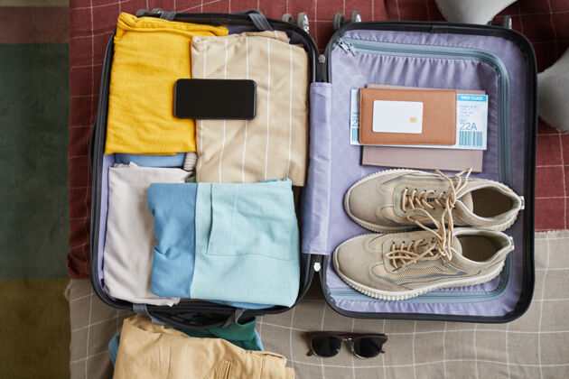 服装高角度的旅行箱 带衣服 鞋子和护照 带旅行票度假行李太阳镜