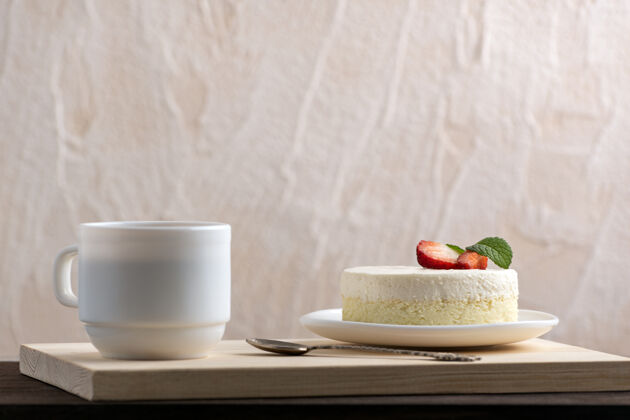 草莓经典的纽约芝士蛋糕和一杯咖啡或茶甜点在咖啡馆烘焙水果糕点